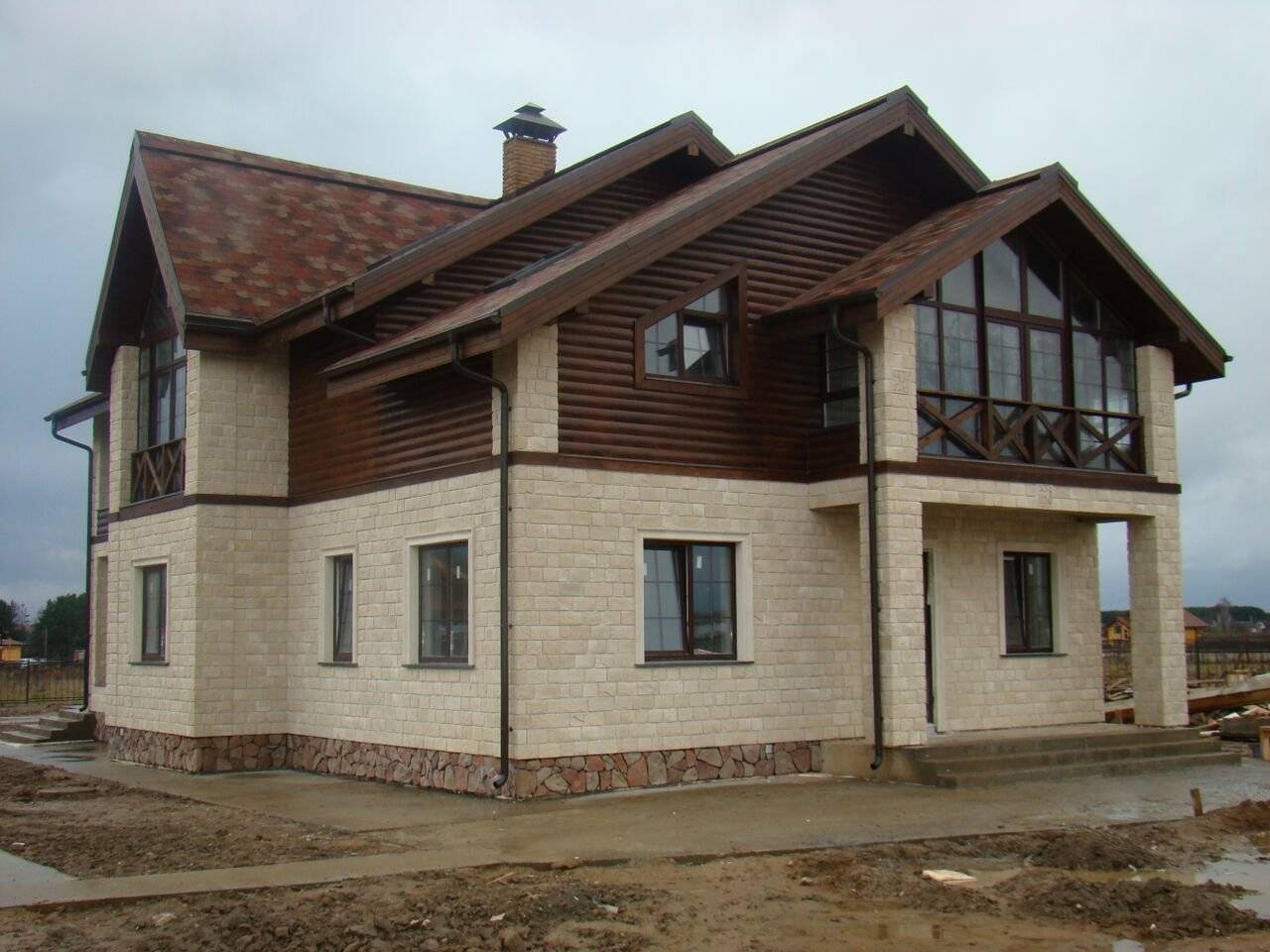 Комбинированная отделка фасада дома штукатуркой и камнем